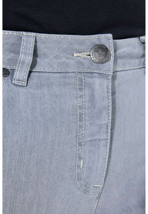 Primo piano della vita di jeans denim grigio chiaro, con bottone di metallo a forma di stella, passante per cintura e dettaglio della tasca cucita su sfondo di tessuto nero.