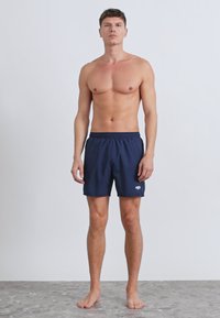 Tengerészkék fürdőnadrág gumis derékrésszel és fehér logóval. Könnyű anyagból készült, vízi tevékenységekhez alkalmas.