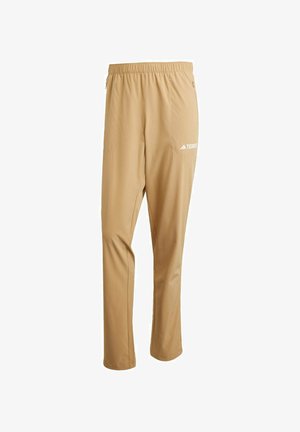 Pantaloni leggeri beige con cintura elastica, tasche laterali e logo bianco sulla coscia sinistra. Tessuto liscio e design a vestibilità dritta.