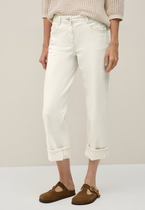 Avklippta vita denimjeans med upprullade fickor, fem fickor och dragkedja. Bärs med bruna mockaskor utan snörning. Texturerad stickad topp.