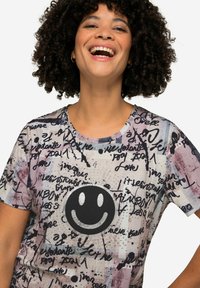 T-shirt à manches courtes avec un motif de graffiti coloré, un visage souriant noir au centre et une texture de tissu douce et lisse.