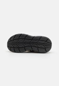 Suela de zapato de goma negra con un patrón de agarre texturizado. Presenta surcos profundos y un diseño elegante para tracción y durabilidad.