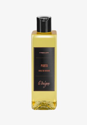 Transparente Flasche mit gelbem Duschöl und schwarzer Etikettierung mit orangefarbener Schrift. Der Deckel ist schwarz; das Design ist schlank und rechteckig.