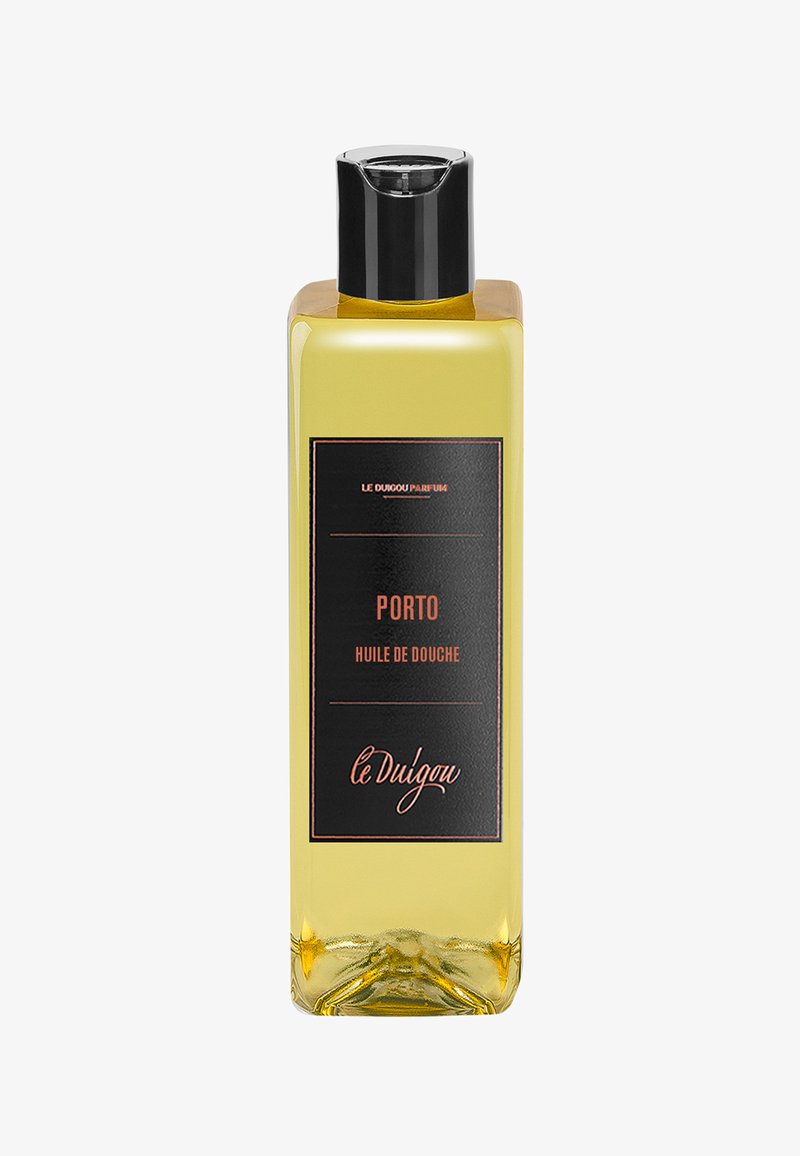 Transparente Flasche mit gelbem Duschöl und schwarzer Etikettierung mit orangefarbener Schrift. Der Deckel ist schwarz; das Design ist schlank und rechteckig.