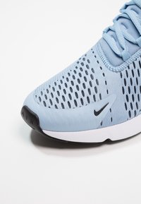 Light blue athletic shoe featuring a breathable mesh upper with black accents, a padded collar, and a contrasting white sole with "AIR" text.