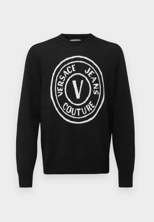 Mustmust värvitud sviiter, mille esiküljel on suur valge ümmargune logo, millel on "VERSACE JEANS COUTURE" ja keskel "V". Ribikantidega kaelus ja varrukate otsad.