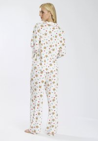 Set di pigiama bianco con maniche lunghe e pantaloni, caratterizzato da un motivo floreale e piccoli motivi di animali. Realizzato in morbido tessuto con una vestibilità rilassata.