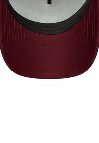 Gorra de béisbol color marrón con visera redondeada, ribete negro y acabado de tela texturizada. El interior presenta un forro de color claro.