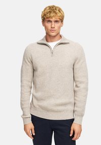 Helles graues Strickpullover aus einem weichen Stoff, mit einem Viertelreißverschluss-Kragen, gerippten Bündchen und einem taillierten Design.