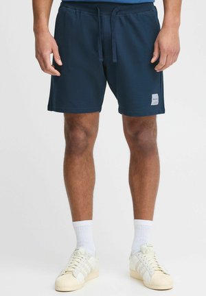 Marineblå shorts lavet af blødt stof, med elastisk talje og snor, sidelommer og et lille logo-patch på benet.