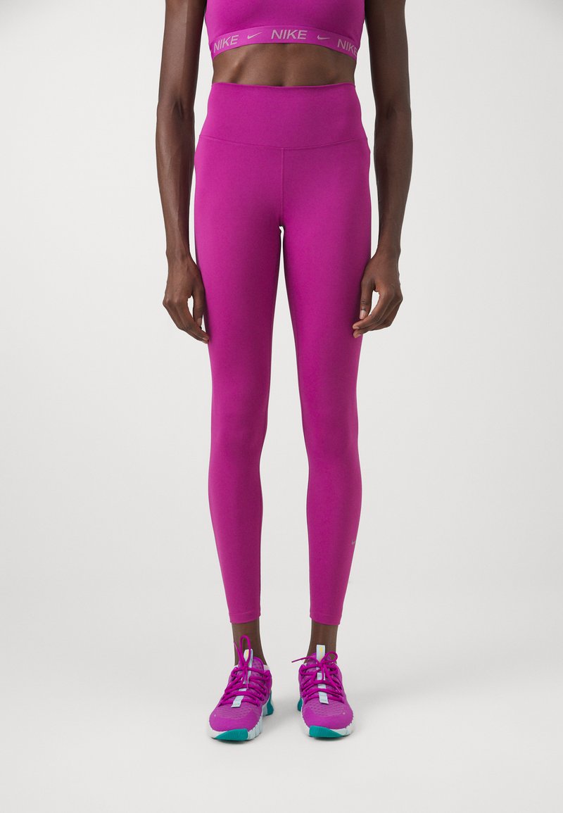 Leggings morados y sujetador deportivo a juego, hechos de material elástico; con cintura alta. Zapatillas deportivas rosa brillante con acentos turquesa.