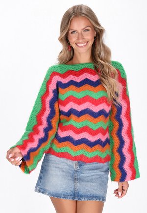 Pulover tricotat cu un model zigzag multicolor în verde, roz, portocaliu și violet. Croială lejeră cu mâneci largi.