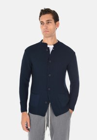 Cardigan a coste navy realizzato in tessuto maglia testurizzato, con scollatura rotonda, chiusura a bottoni completa e due tasche frontali.