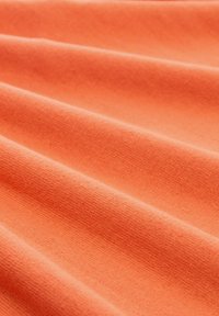 Textielstof in een helder koraalkleur met een gladde textuur, voorzien van subtiele golven en plooien die diepte en dimensie creëren.