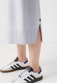 Lyseblå ribbet strikket kjole med sidesliss, kombinert med hvite Adidas-sneakers med svarte striper og grå detaljer.