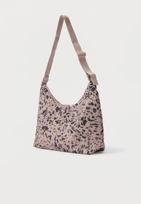 Μικρή τσάντα ώμου σε μπεζ χρώμα με ρυθμιζόμενο λουρί και μαύρο αφηρημένο μοτίβο λεοπάρ, στέκεται όρθια σε λευκό φόντο.