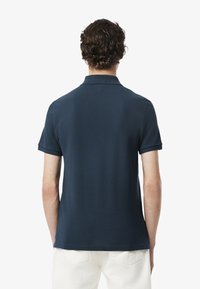 Camisa polo azul marino de manga corta, con un cuello clásico y un ajuste relajado. Textura suave con un respaldo sin costuras y un detalle de costura sutil.
