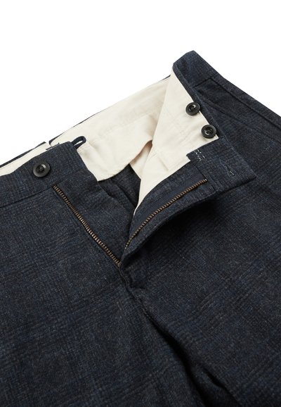 Ciemnoniebieskie spodnie z teksturowanego materiału, z zasuwanym zamkiem błyskawicznym, dwiema czarnymi guzikami w pasie i kremowym podszewką.