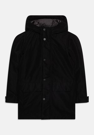 Parka nera con cappuccio, bottoni a pressione frontali, due grandi tasche con patta e cinturini regolabili ai polsi su sfondo semplice.