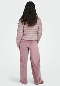 Heledad roosa puffertagi horisontaalse tikandiga, kombineeritud pehme roosa laia jalgadega pükstega. Mõlemad rõivad omavad pehme ja sametise tekstuuri.