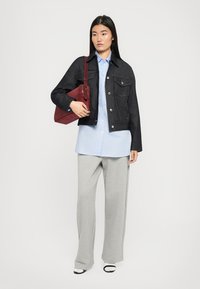 Denimjakke, lyseblå skjorte med knapper, grå vide bukser og en maroon taske. Outfittet har kontraststing og lomme detaljer.