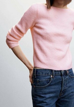 Pull en rose pâle côtelé à manches trois-quarts, associé à un jean bleu foncé avec fermeture à bouton et poches avant.