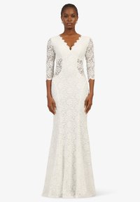 Weißes Spitzenkleid mit tailliertem Oberteil, gewelltem Ausschnitt, Dreiviertelärmeln und ausgestellt geschnittenem Saum mit filigranen Blumenmustern.