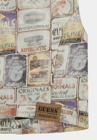 Giubbotto di jeans con un colorato patchwork di loghi e etichette vintage, dotato di un'etichetta in pelle marrone del brand. Tessuto morbido e текстurizzato con un design accorciato.