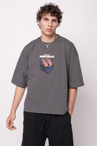 Šedé oversized tričko s krátkým rukávem, na kterém se nachází modrooranžový grafický motiv kočičí tváře obklopené plameny. Černé šortky doplňují tento outfit.