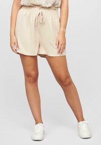 Shorts beiges à cordon de serrage avec une taille élastique, fabriqués à partir d'un tissu léger, présentant une coupe décontractée et une texture lisse.