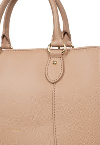 Borsa a mano in pelle beige con finitura testurizzata, hardware dorato, manici doppi e logo nella parte inferiore. Design semplice ed elegante.