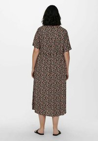 Floral-patterned black dress with short sleeves, mid-calf length, loose fit, and a gathered waist detail. Sandals visible at the bottom.