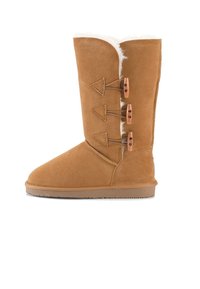 Stivale in suede beige con rivestimento in pelliccia sintetica, gambale alto e tre chiusure decorative a toggle sul lato. Punta rotonda e suola in gomma piatta.