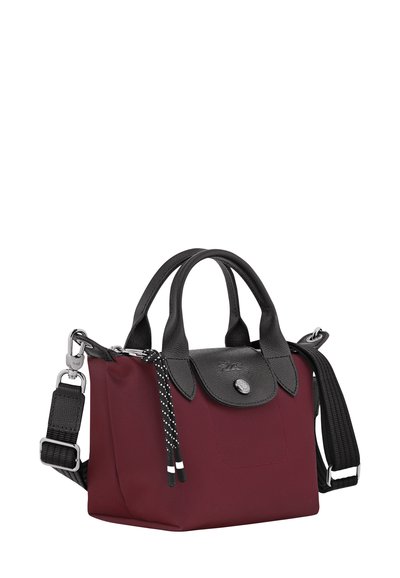 Burgundy nylon handbag with black leather accents, double handles, removable shoulder strap, and a decorative polka dot tassel.