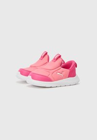 Zapatillas rosa sin cordones con una textura suave, con una suela blanca y acentos elásticos. Logo de Puma en blanco en el lado.