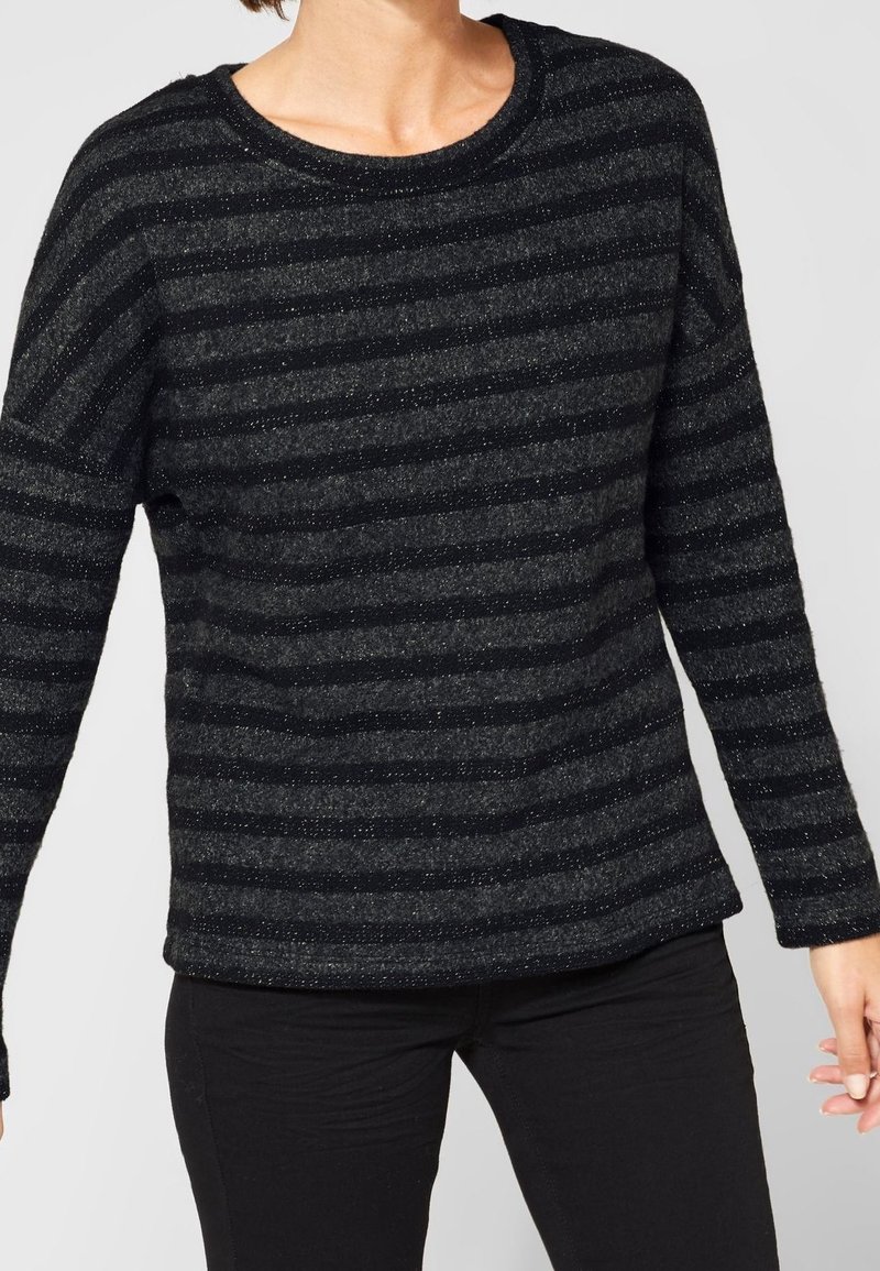 Svart och grårandig tröja med långa ärmar, rund halsringning och en strukturerad yta som har subtila glittrande detaljer.