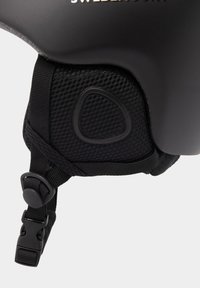 Zwarte helm met een gladde schaal, gestructureerde mesh voering, verstelbare banden en een veilige gesp. Logo gedrukt aan de buitenkant.