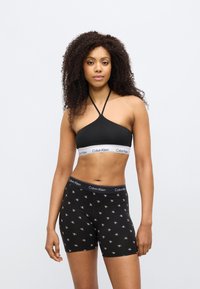 Μαύρο bralette με σχέδιο halter neck και λωρίδα με το λογότυπο Calvin Klein· σετ με μαύρα boxer σορτς με επαναλαμβανόμενο μοτίβο λογότυπου.