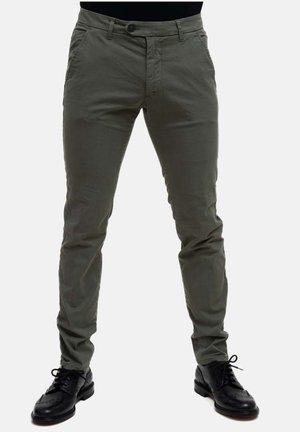 Pantaloni slim fit verde oliva con chiusura a bottone, tasche frontali e una texture liscia, abbinati a scarpe eleganti in pelle nera.