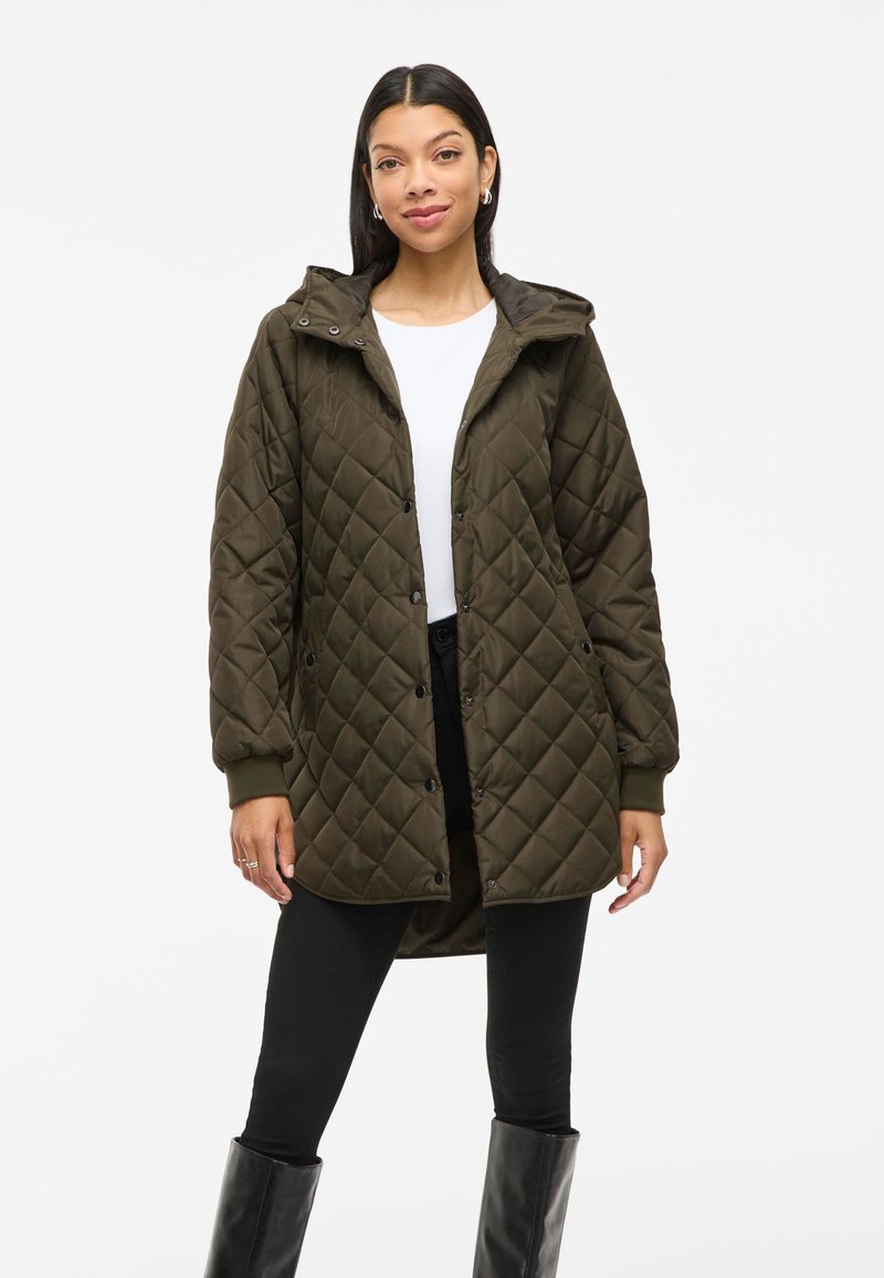 Parka olive vert matelassée avec capuche, boutons-pression, poignets côtelés et coupe mi-longue. Fabriquée dans un matériau lisse et isolant.