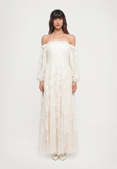 Hochzeitskleid mit schulterfreiem Ausschnitt in Creme, langen durchsichtigen Ärmeln, verziert mit floralem Stickereien und einem gerafften Rock, abgerundet mit einer fließenden Silhouette.