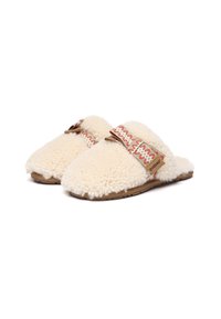 White fur-lined slippers with a soft texture, featuring a patterned fabric strap and a brown rubber sole. Accented with a logo tag.