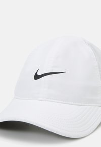 Weißer Sportcap aus leichtem Stoff, mit einem schwarzen Swoosh-Logo auf der Vorderseite, einem gebogenen Schirm und gestickten Details.
