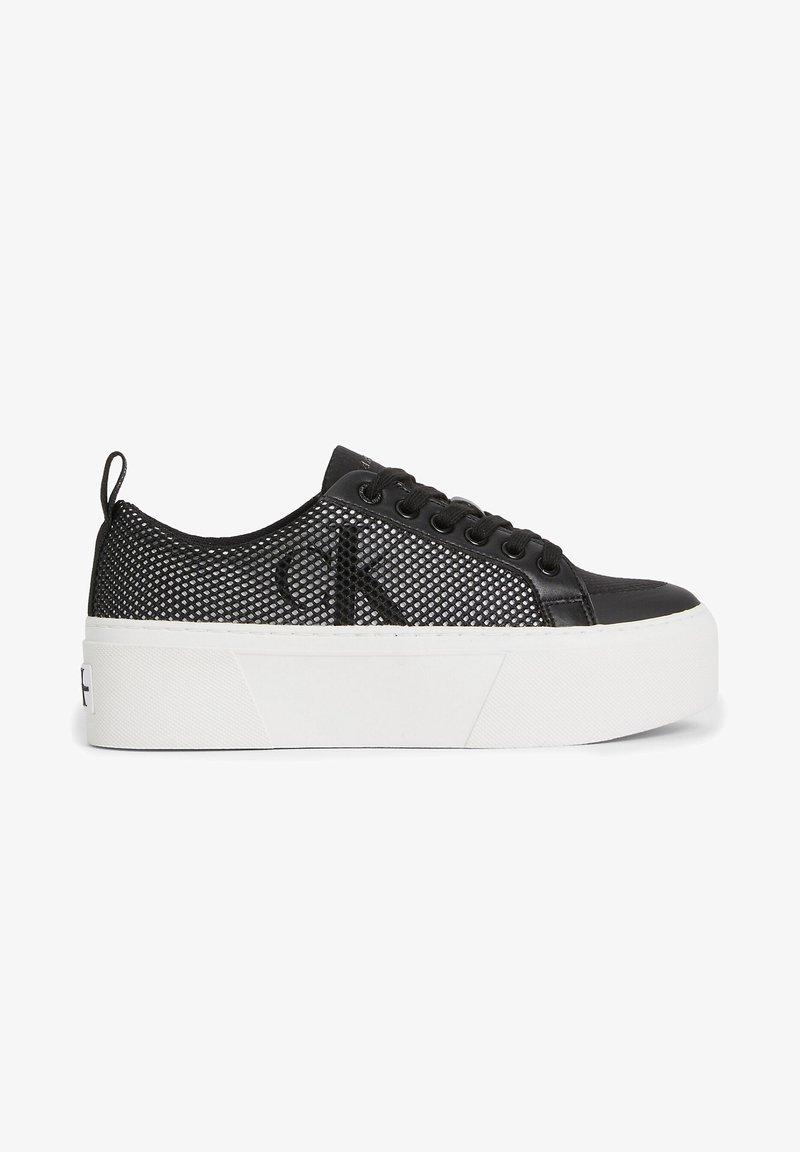 Black platform sneakers with mesh upper, smooth leather accents, round toe, and flat white sole. Features black laces and logo detail.