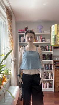 Svetlo modra denim kratka majica s kvadratnim izrezom in širokimi naramnicami. Usklajena s črnimi cargo hlačami, ki imajo stranske žepke.