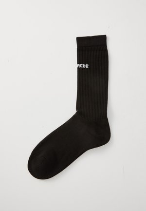 Calcetín negro de canalé con texto parcial en blanco "RED2" cerca del puño superior, colocado sobre un fondo blanco liso.