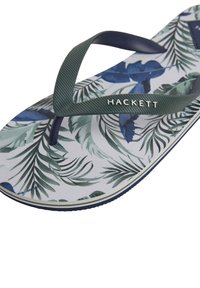 Infradito con suola bianca caratterizzata da motivi tropicali di foglie blu e verdi, cinturini testurizzati verde scuro e un dettaglio del logo.