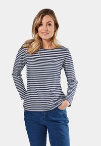 Marineblauwe en wit gestreepte blouse met lange mouwen, een ronde halslijn en een relaxte pasvorm, gedragen met blauwe denim jeans. Zachte stofstructuur.