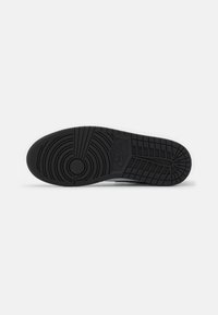 Czarna gumowa podeszwa do sneakersów z teksturowanym wzorem przyczepności, zawierająca okrągłe logo oraz zróżnicowaną głębokość bieżnika dla lepszej przyczepności.