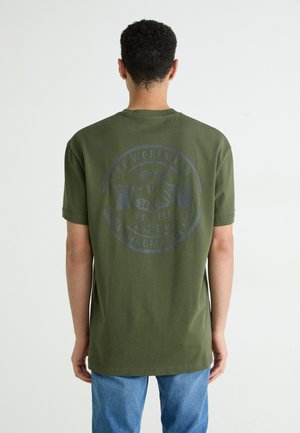 T-shirt verde oliva con maniche corte e scollo rotondo, caratterizzato da un grande logo grigio e testo sul retro, realizzato in morbido cotone.